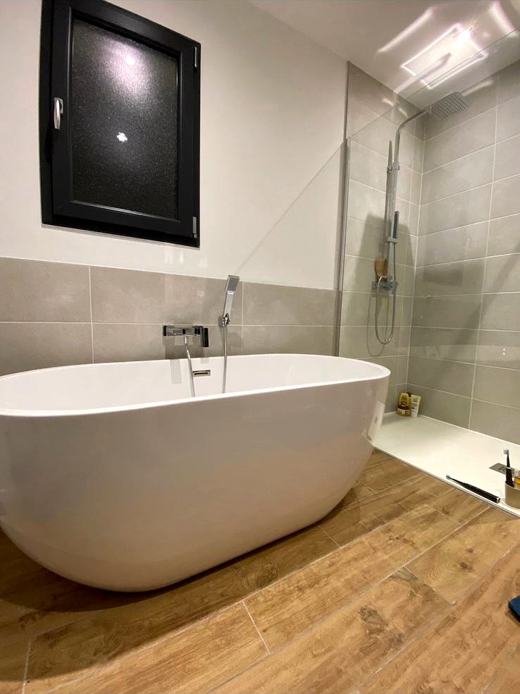 Salle de bain rénovée avec baignoire îlot blanche et douche à l'italienne vitrée